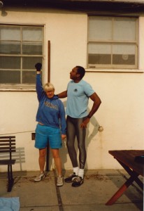 Zan, always irreverent, imitates Tommie Smith’s black-gloved salute in the 1968 Olympic Games while Tommie himself patiently looks on, 1986